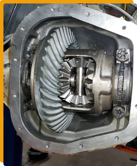 Transmission Repair In Tomball TX At Jon’s Auto & Diesel Repair. A close-up view of a differential gear assembly inside a metal housing, showing the ring gear, pinion gears, and other internal components.