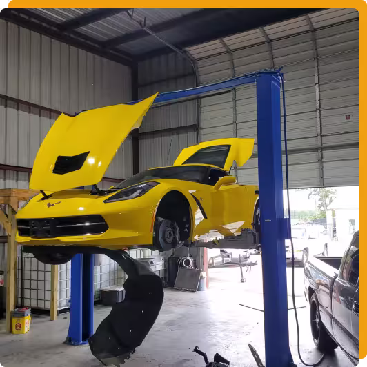 European & Luxury Vehicle Repair in Tomball TX At Jon’s Auto & Diesel Repair. A yellow Chevrolet Corvette with its hood and trunk open is lifted on a blue car lift inside a garage, with its wheels removed for maintenance.
